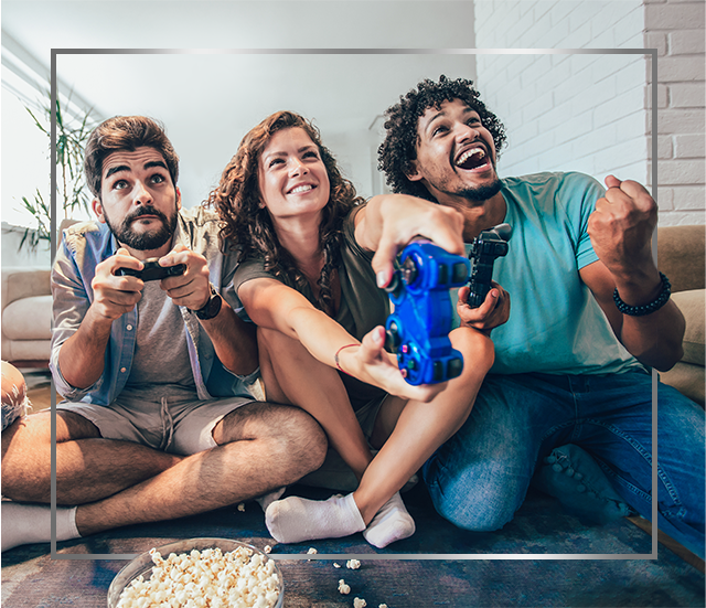 Group of young smiling people sitting on floor and playing video games, happy after Canespro fungal nail treatment