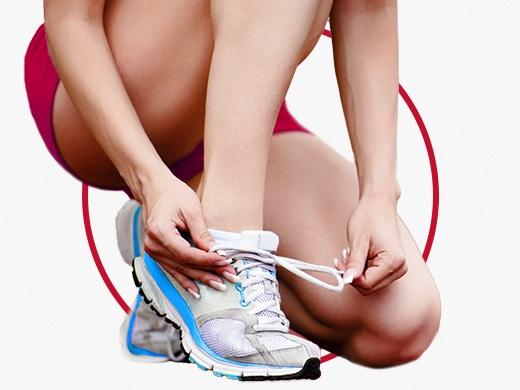 Woman in shorts wearing white sneakers tying shoelace