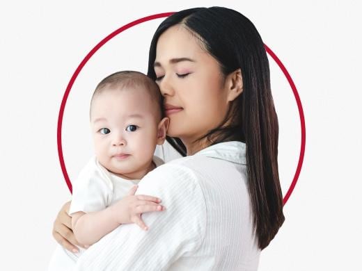 Woman holding baby in her arms happy after Canesten fungal nappy rash treatment