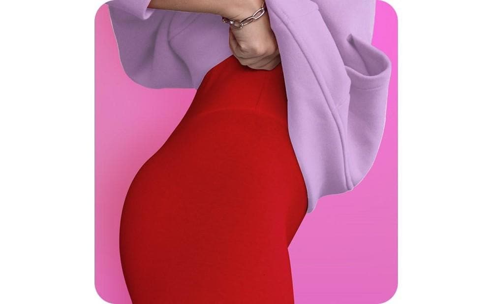 Close up cropped photo of a woman in a pink sweatshirt and red leggings pulling up her bottoms
